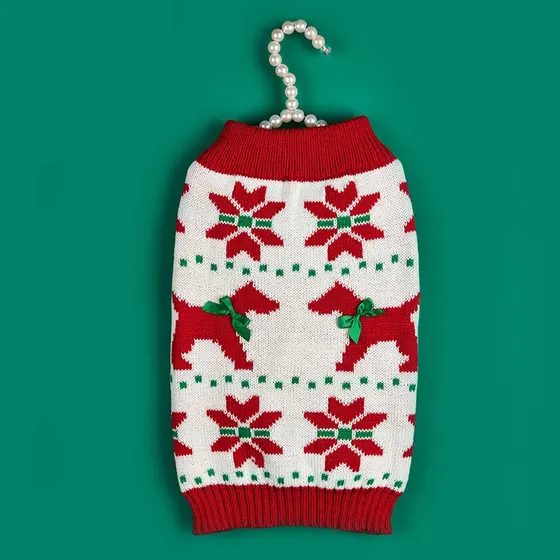 Knitted holiday sweater with red dog and poinsettia patterns hanging on a pearl hanger.