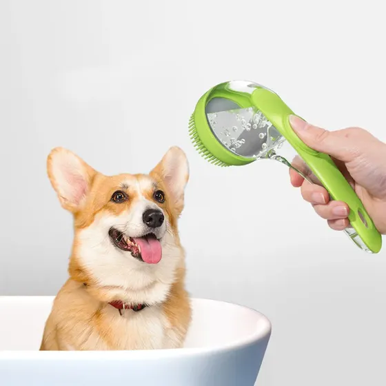 A hand holds a green pet shower sprayer brush over a corgi in a white bathtub.