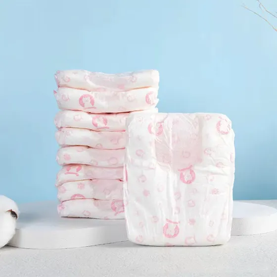 Stacked white baby diapers with pink patterns displayed on a white stand against a light blue background.