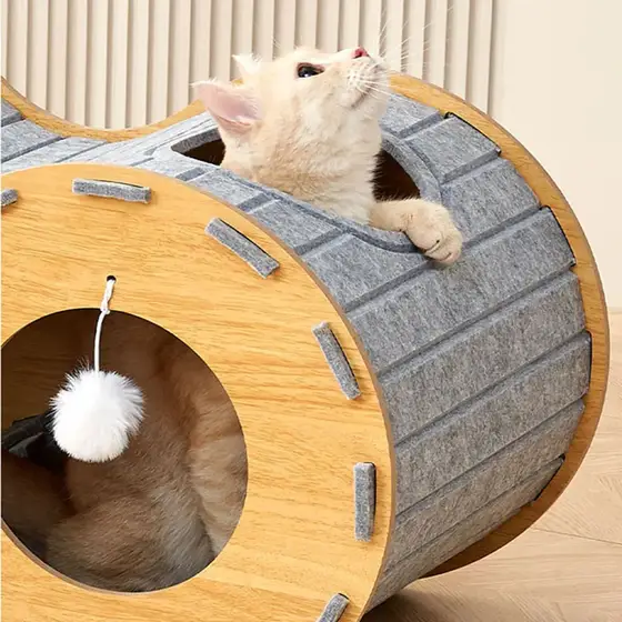 Cream cat peeking out of a wooden and felt cat tunnel toy with a hanging ball