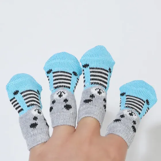 Hand with four fingers wearing small knitted socks with blue toes, grey cuffs, and black paw prints