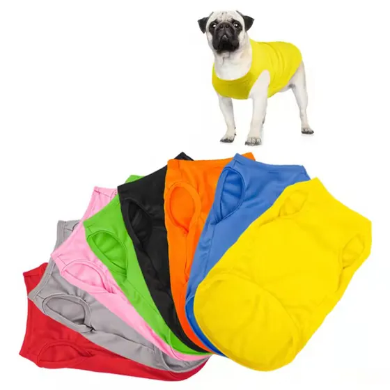 A pug wearing a yellow shirt standing above a fanned-out stack of colorful shirts