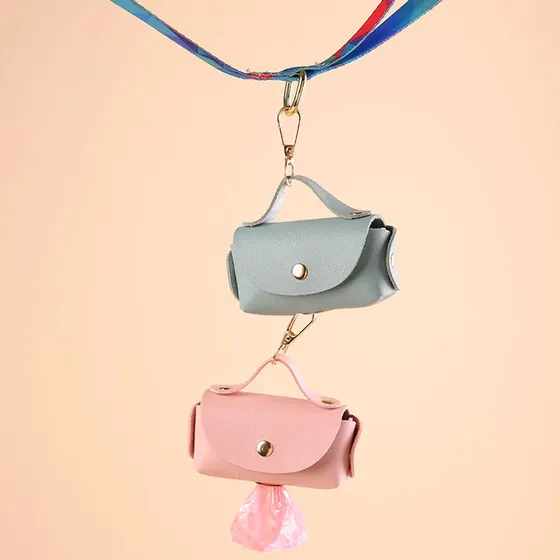 A pink and a blue pet poop bag dispenser hanging from a leash strap.