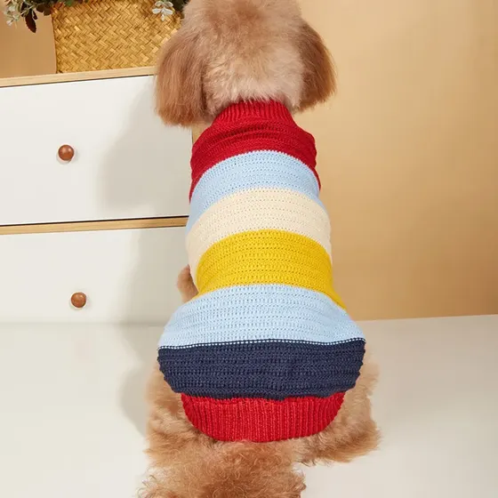 A fluffy brown dog is seen from behind wearing a colorful striped knitted sweater.