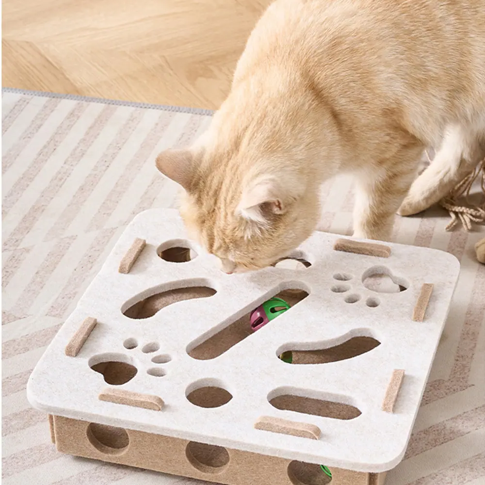 Orange tabby cat playing with a wooden puzzle box toy containing hidden balls.