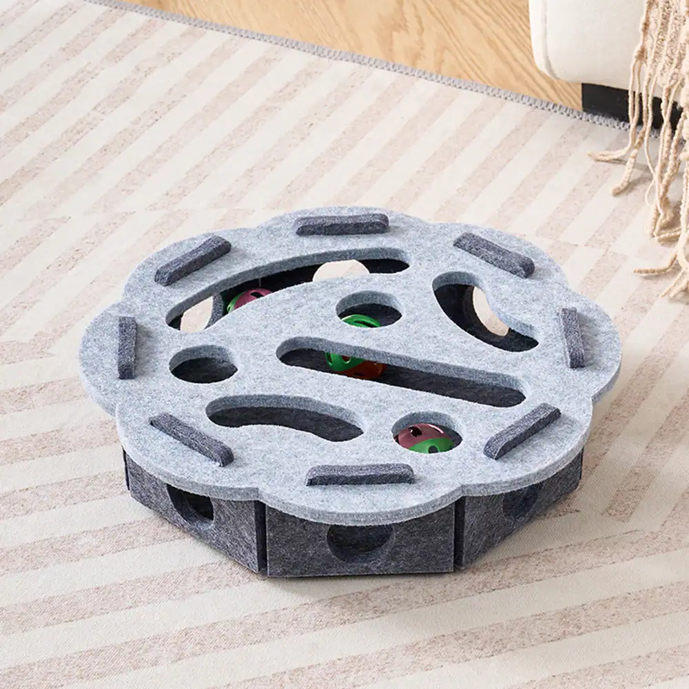 Grey felt puzzle feeder with colorful balls on a striped rug