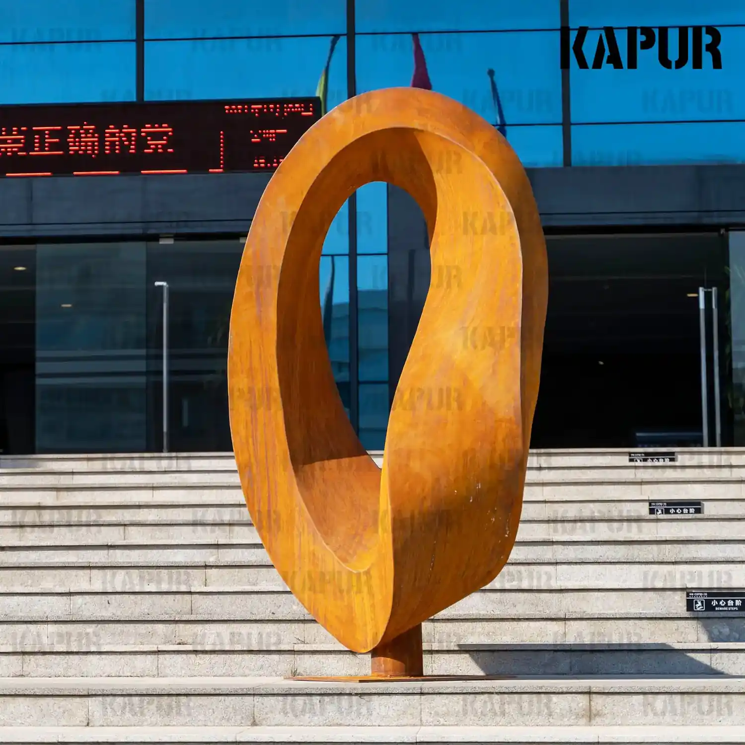 Second view of the corten steel Möbius ring sculpture, highlighting the curved form and natural rust patina