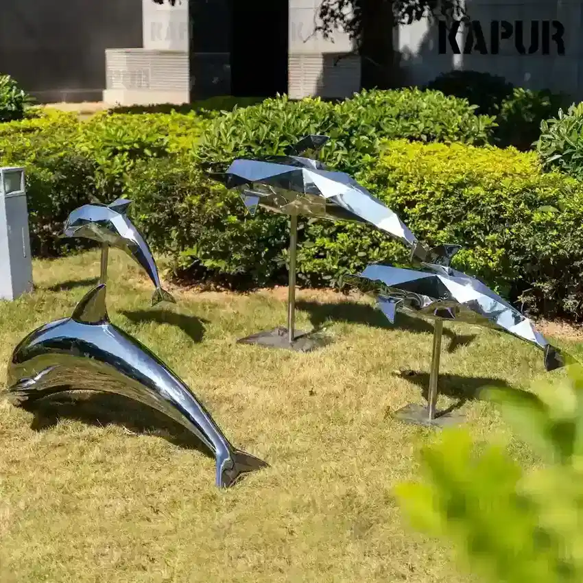 Second view of the stainless steel dolphin sculpture showing the curved reflective surface and side profile
