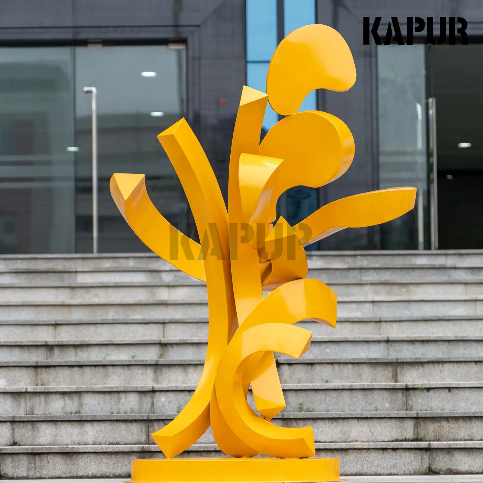 Abstract stainless steel sculpture in a modern outdoor garden setting, reflecting sunlight with a polished surface