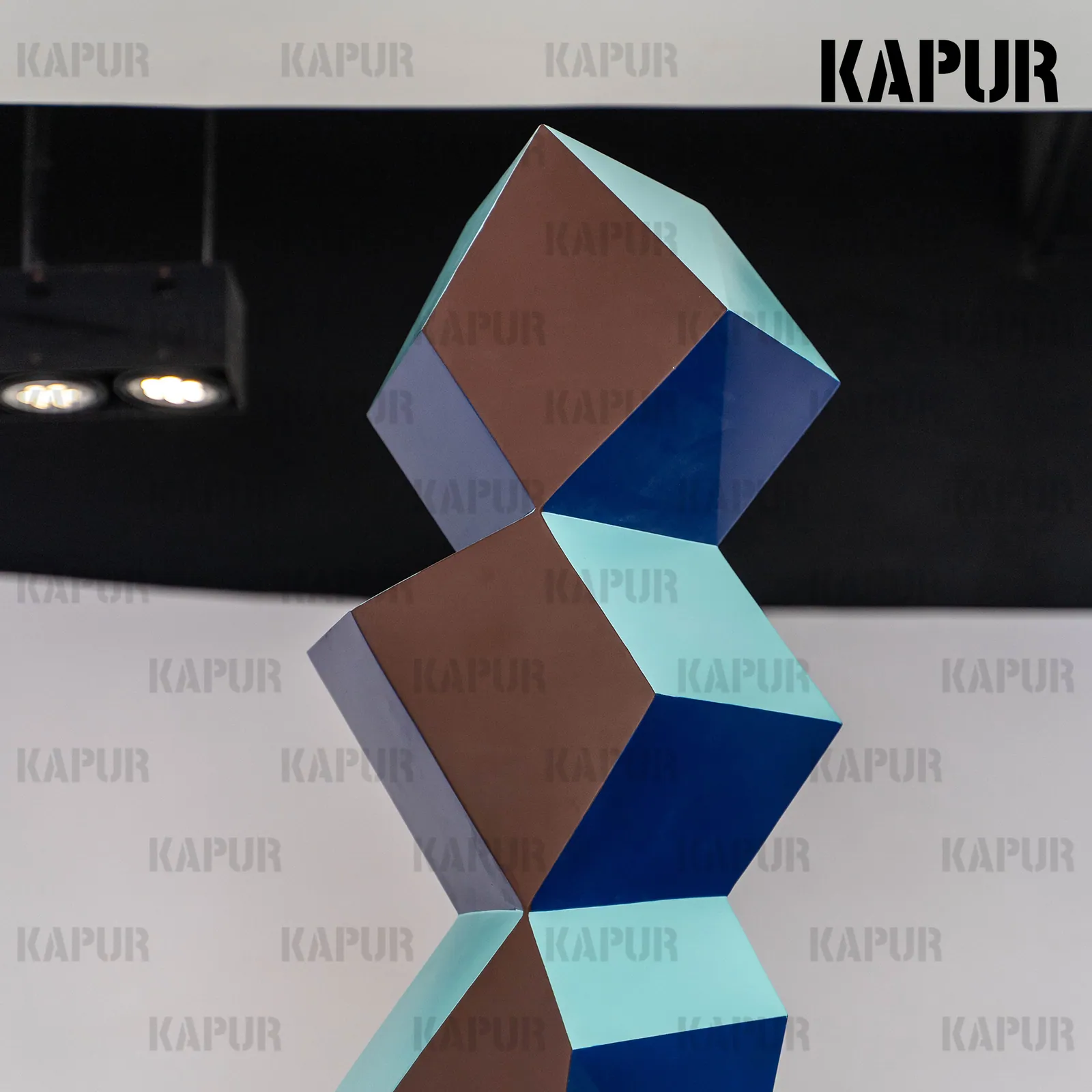 Second view of the rhombus sculpture showing the angular geometry and continuous polished finish