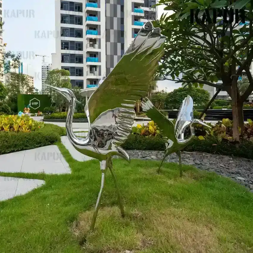 Side view of the stainless steel bird sculpture showing its curved wings and reflective surface