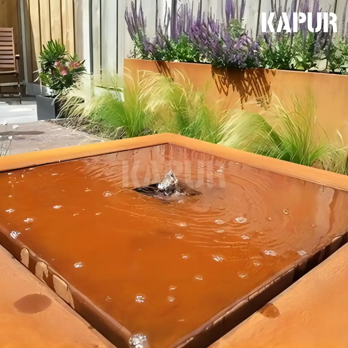 Corten steel outdoor garden waterfall sculpture with natural rust patina, placed in a landscaped garden setting