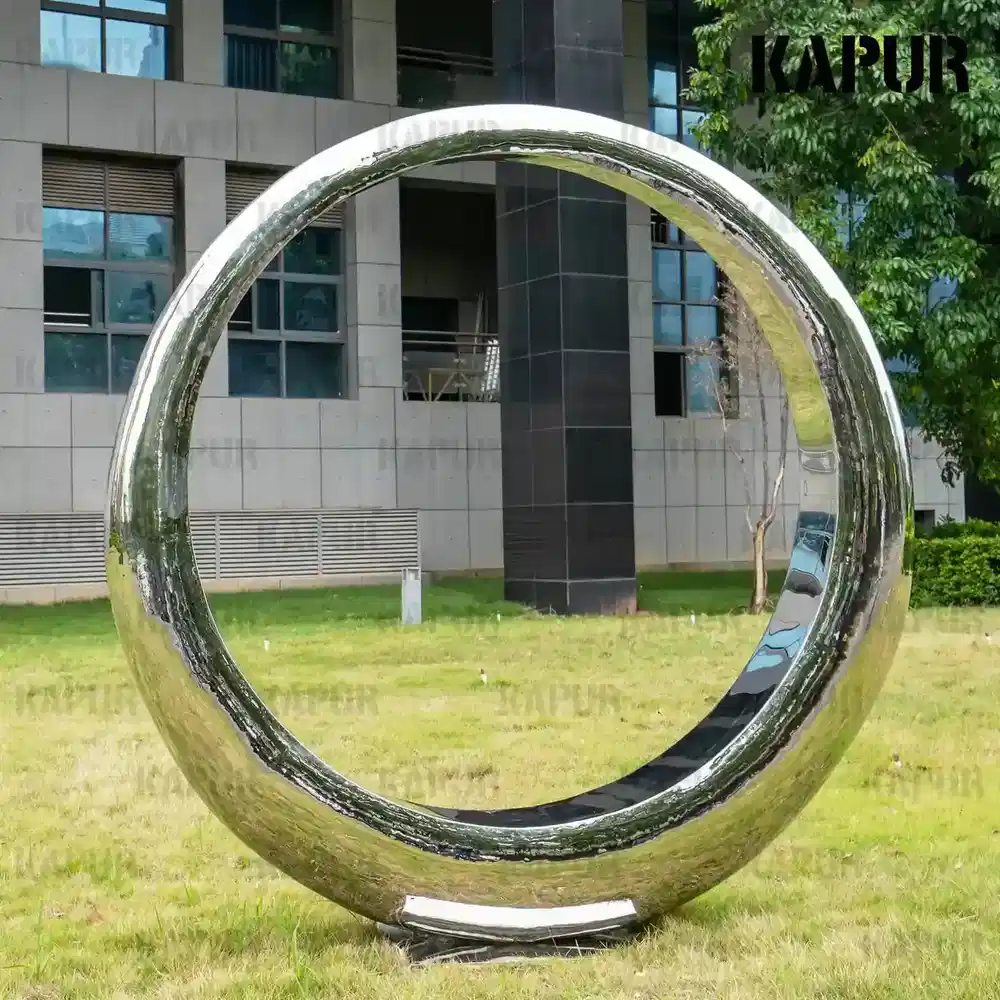 Second view of the moon sculpture showing the curved reflective surface under daylight