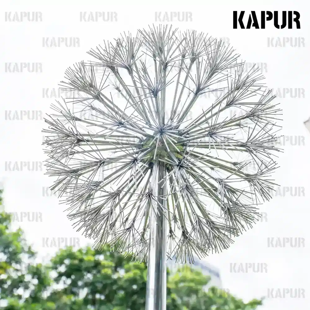 Polished stainless steel dandelion-shaped sculpture standing in a modern garden setting
