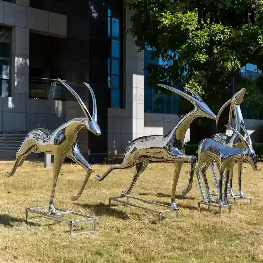 Side view of the stainless steel deer sculpture showing its curved body and reflective surface