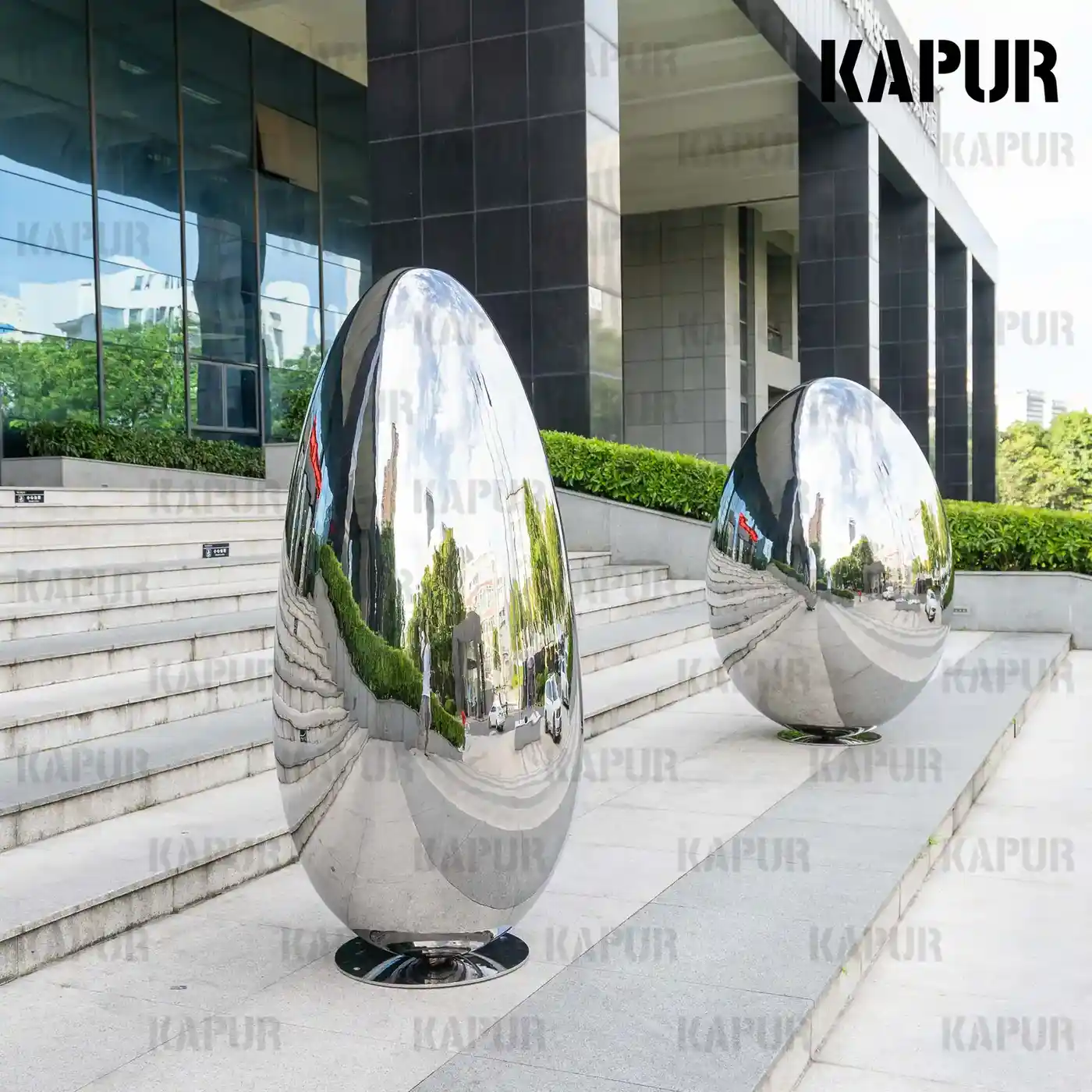 Second view of the egg-shaped stainless steel sculpture showing the smooth curved finish and base plate detail