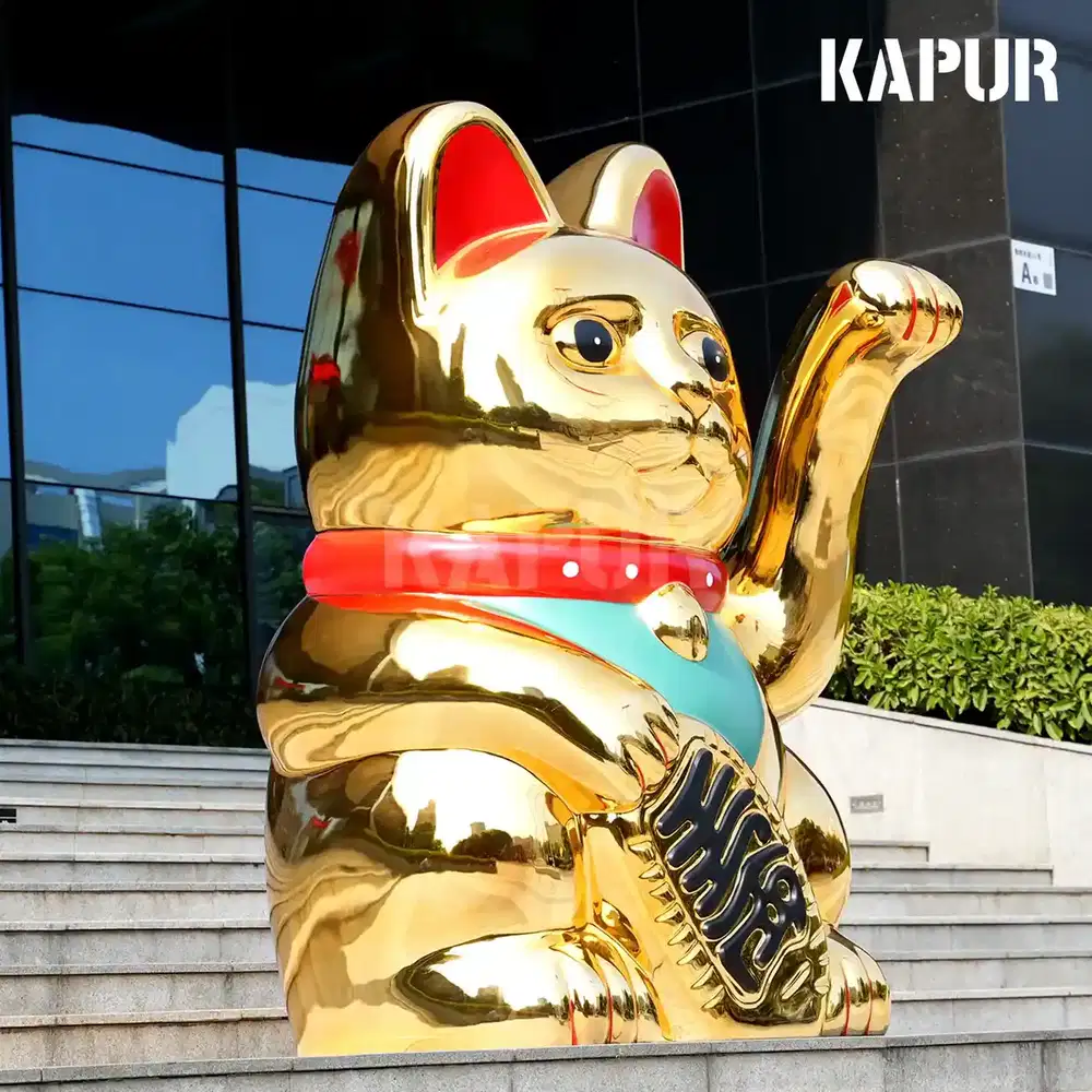 Second view of the beckoning cat sculpture showing the curved reflective surface and detailed hand gesture