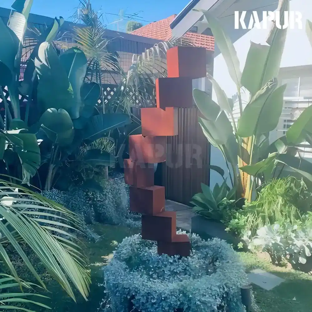 Large corten steel sculpture in the shape of dangerous building blocks standing in an outdoor garden setting