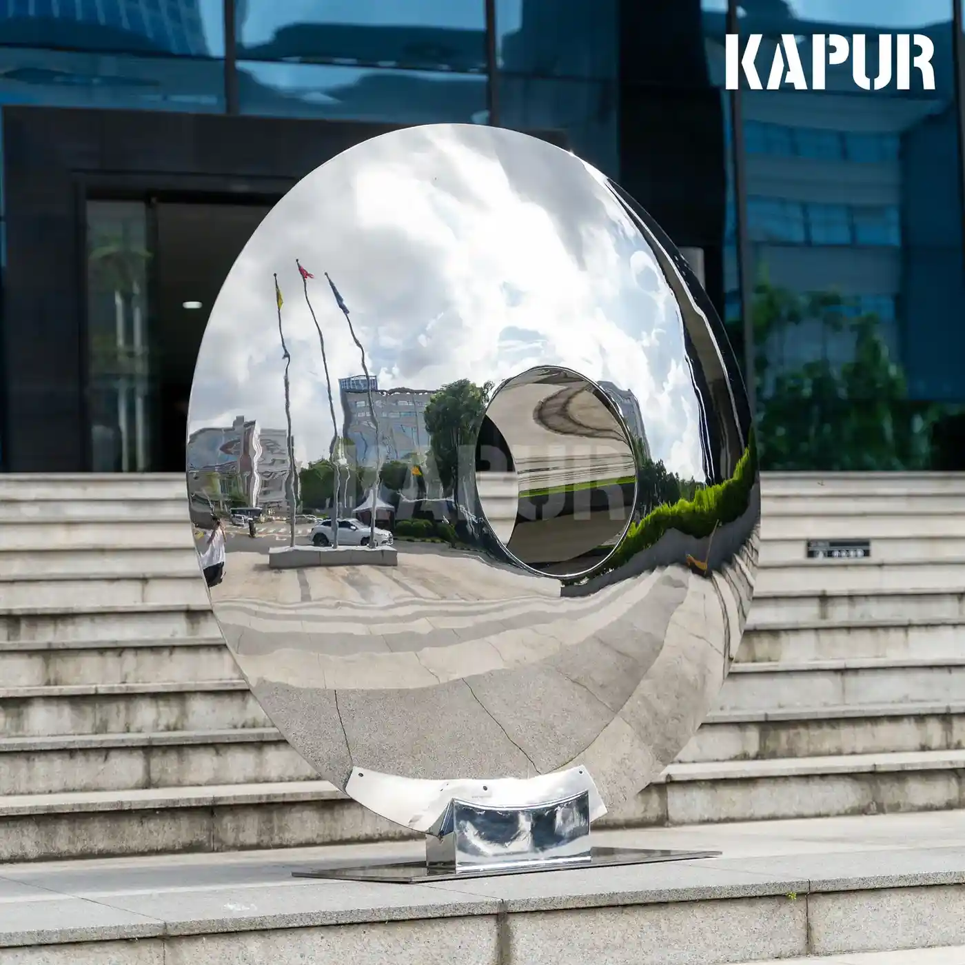 Large mirror-polished stainless steel eye sculpture on a civic plaza