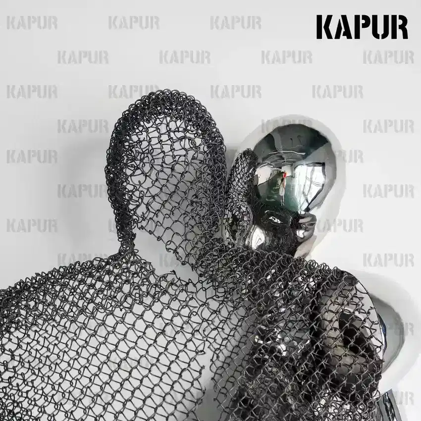 Second view of the abstract human body embrace sculpture showing the curved reflective surface and embrace form