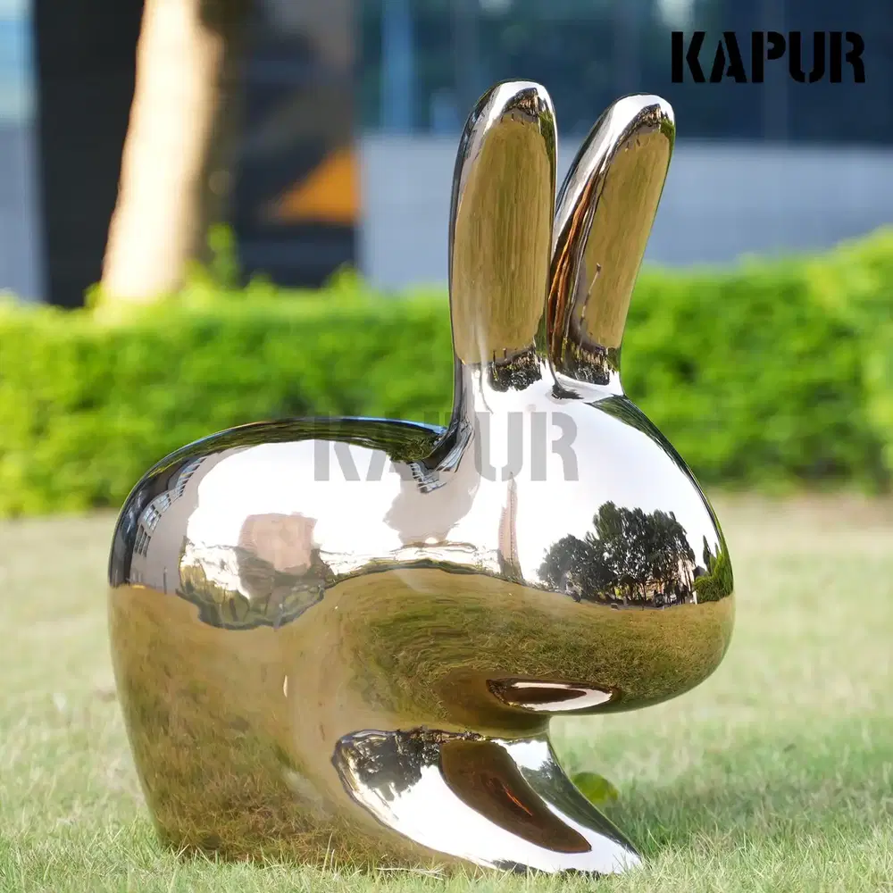 Polished stainless steel rabbit sculpture standing on a paved outdoor plaza