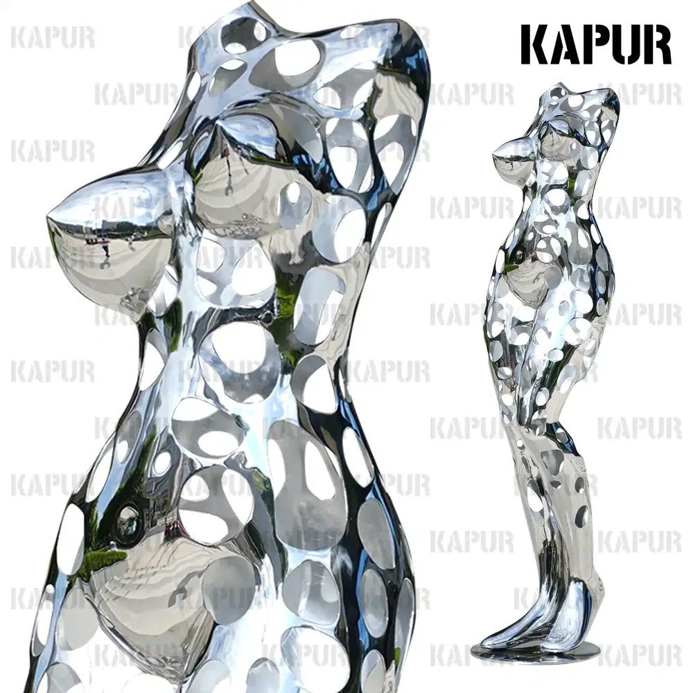 Polished stainless steel hollow woman sculpture standing on a paved outdoor plaza, viewed from the front