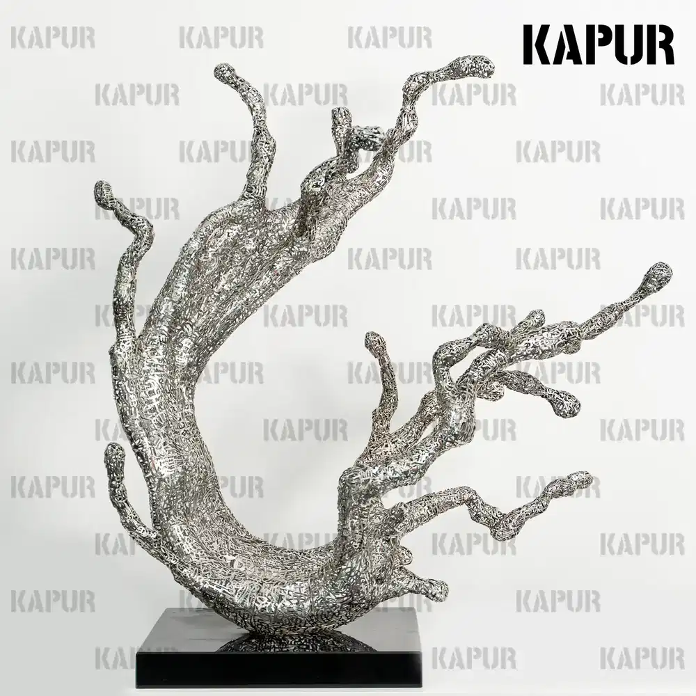 Polished stainless steel hollow wave sculpture standing on a paved outdoor plaza, reflecting the sky and surrounding architecture