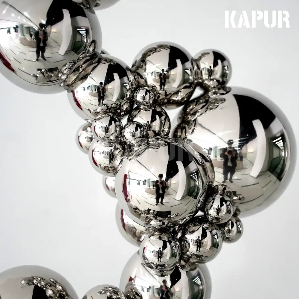 Second view of the polished stainless steel sphere showing the reflective surface under daylight
