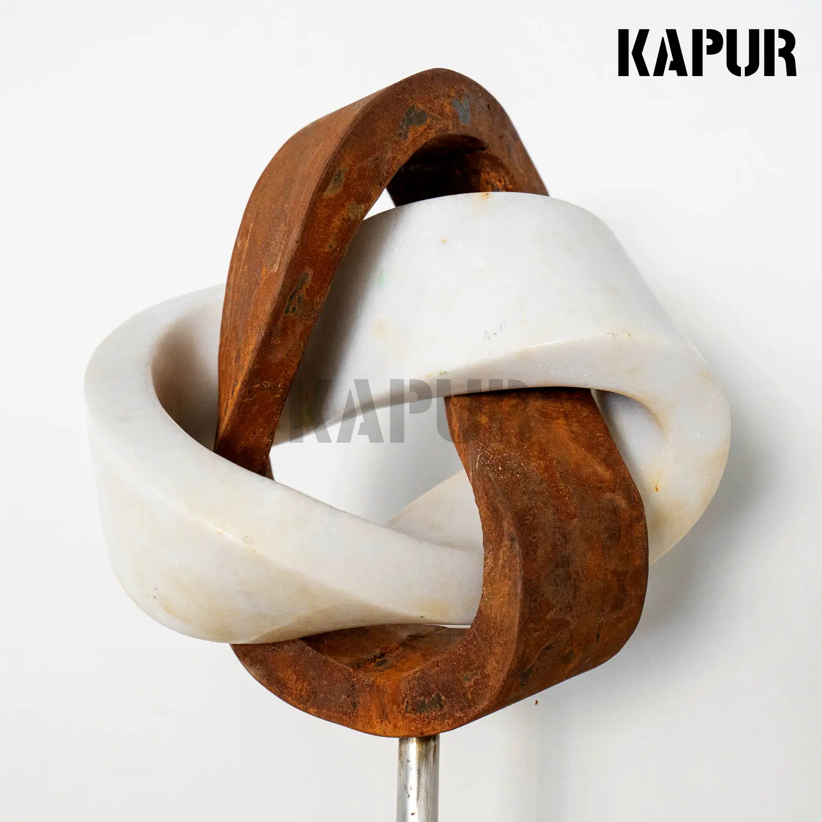 Corten steel and marble sculpture with a modern creative form standing in a garden setting