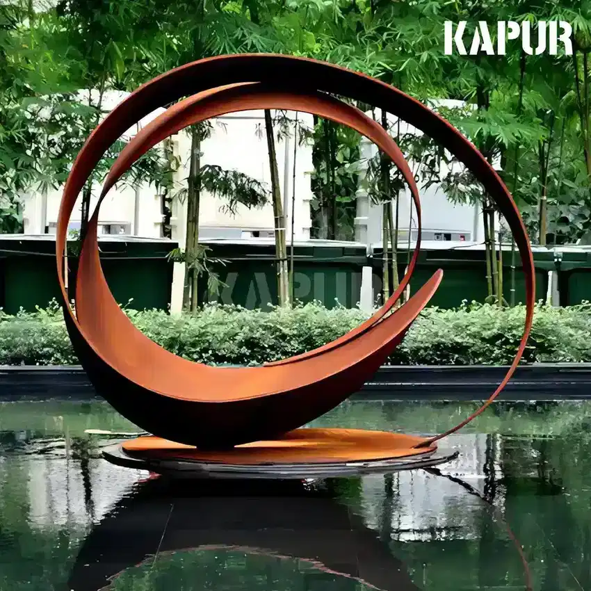 Abstract corten steel sculpture in a garden setting with natural rust patina, standing on a paved outdoor surface