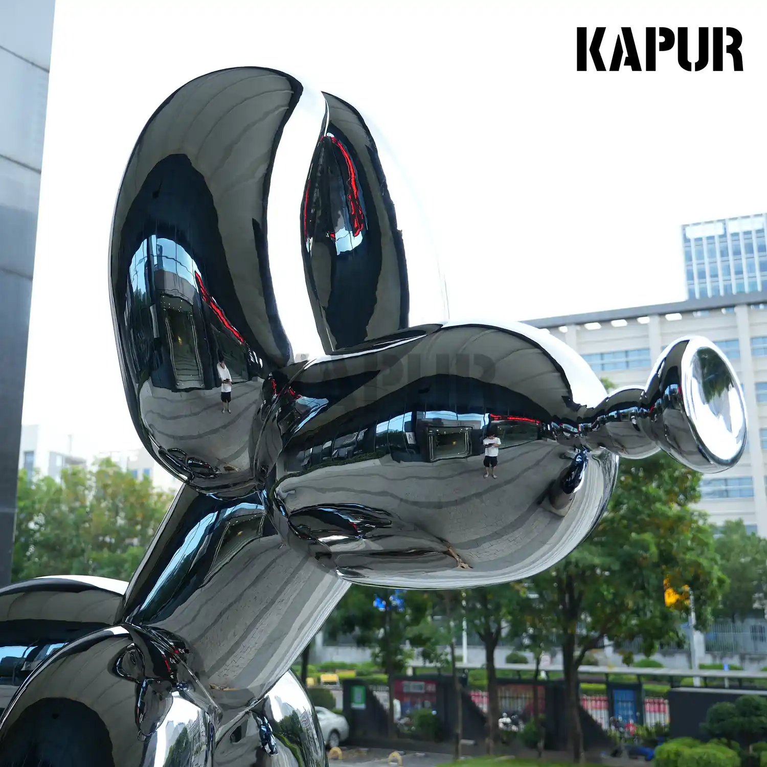 Second view of the stainless steel balloon dog sculpture showing the curved reflective form and base plate detail