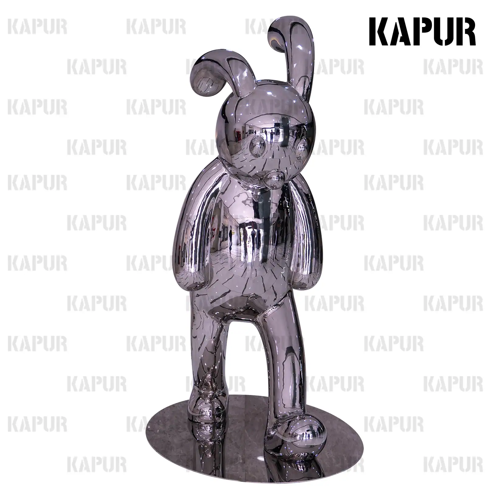 Polished stainless steel rabbit animal sculpture standing in a garden setting with greenery around it