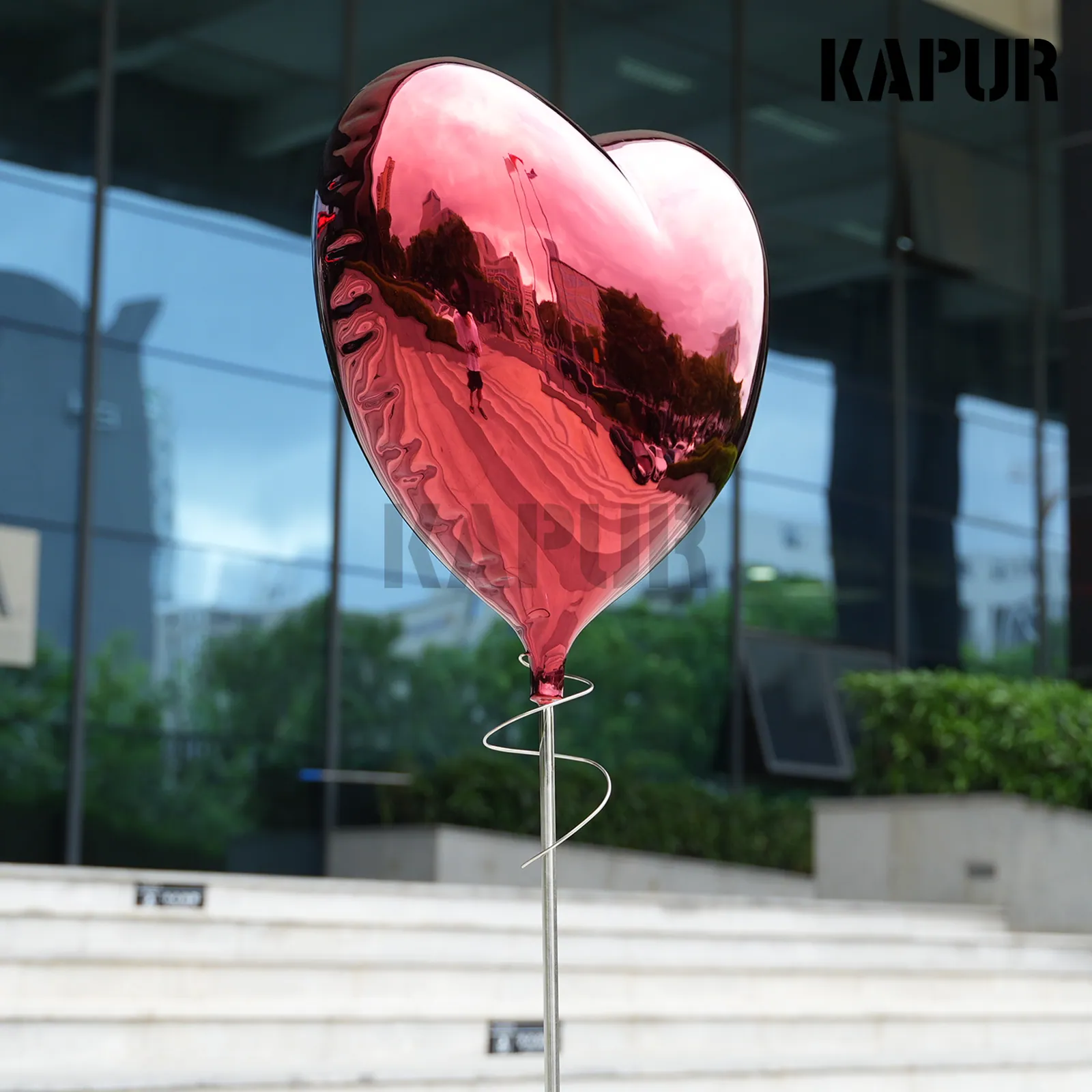 Second view of the stainless steel love balloon sculpture showing the curved reflective surface and seamless welds