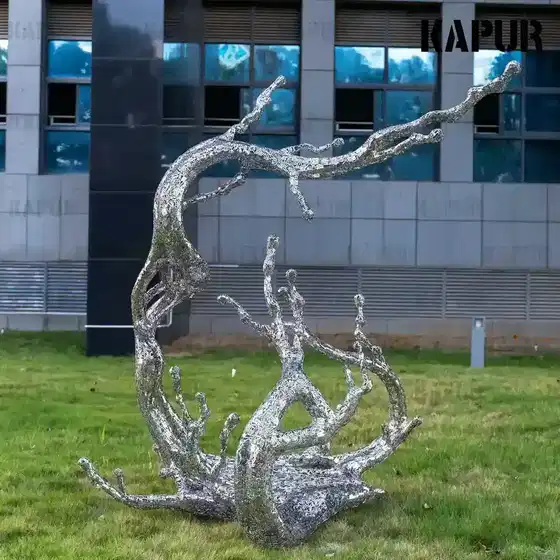 Abstract stainless steel sculpture shaped as a letter, water and flower standing on a paved outdoor plaza