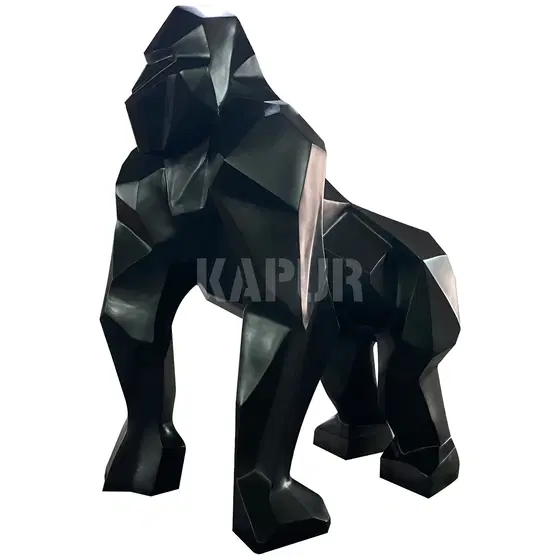 Black fiberglass origami-style gorilla statue standing in a modern garden setting with folded geometric forms