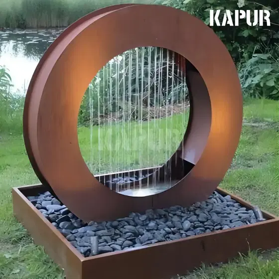 Corten steel round water portal sculpture with a waterfall feature in an outdoor garden setting