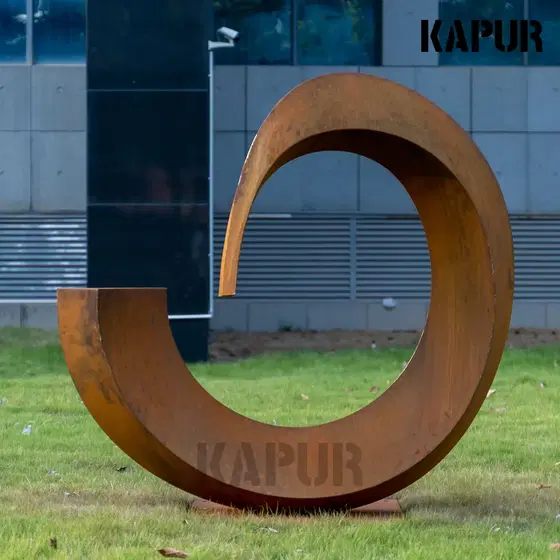 Corten steel arc-shaped sculpture standing in a garden setting with natural vegetation around it