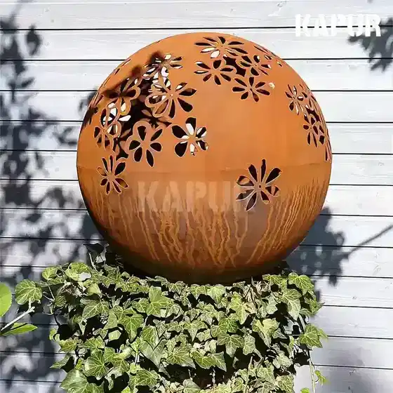 Laser-cut corten steel garden metal ball sculpture standing in a garden setting with natural rust patina