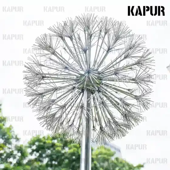 Polished stainless steel dandelion-shaped sculpture standing in a modern garden setting