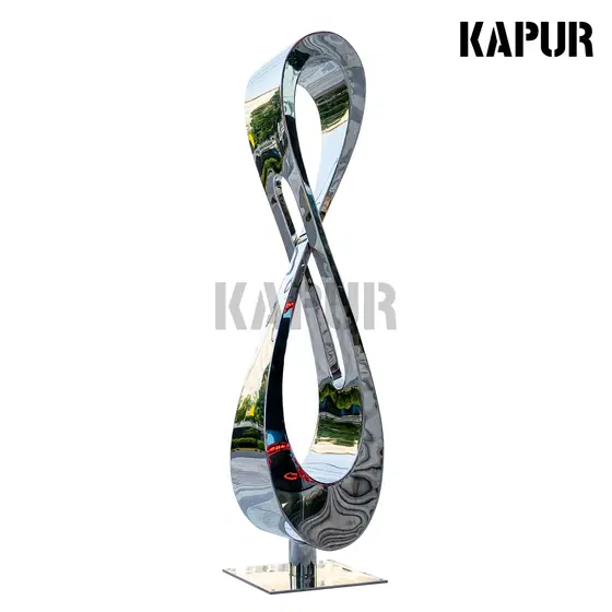 Large polished stainless steel sculpture in modern art style standing in an outdoor garden setting