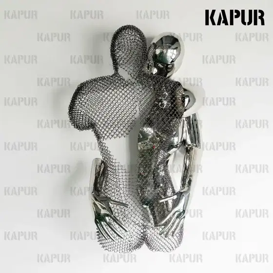 Polished stainless steel abstract human body embrace sculpture standing on a paved outdoor plaza