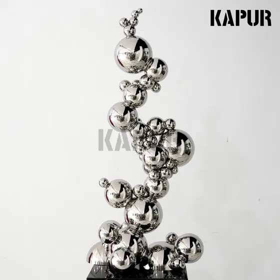 Mirror-polished stainless steel sphere sculpture standing on a paved outdoor plaza