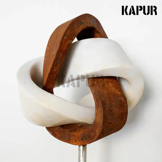 Corten steel and marble sculpture with a modern creative form standing in a garden setting