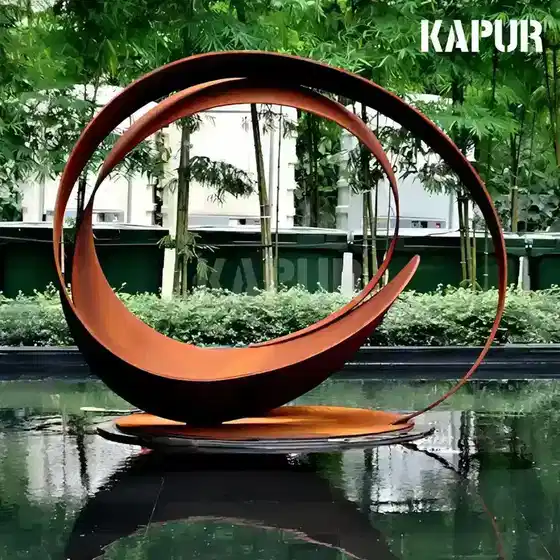 Abstract corten steel sculpture in a garden setting with natural rust patina, standing on a paved outdoor surface