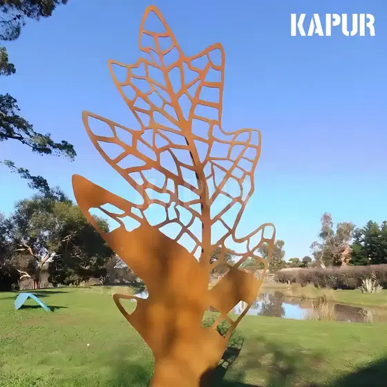 Corten steel leaf skeleton sculpture standing in an outdoor garden, showing natural rust patina and open structure