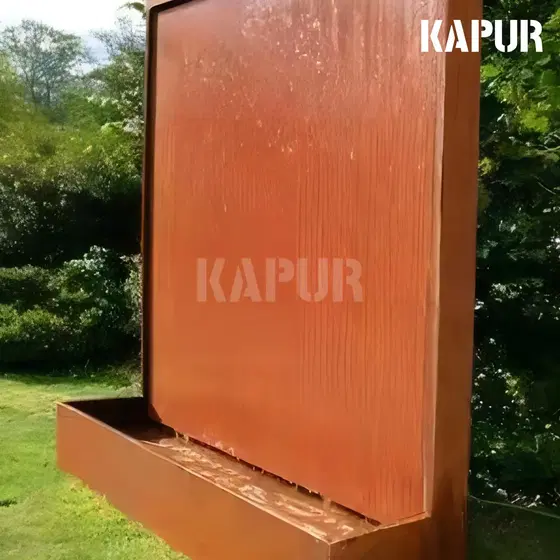 Corten steel water wall sculpture in an outdoor garden setting with water flowing down the rusted surface