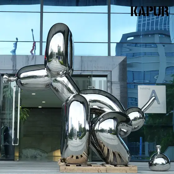 Large stainless steel balloon dog sculpture standing in an outdoor plaza, mirror-polished surface reflecting the sky