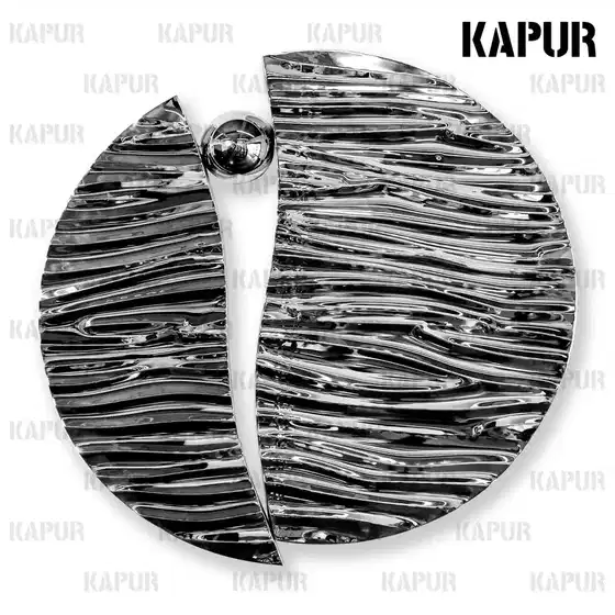 Polished stainless steel water ripple wall sculpture mounted on a white interior wall with soft ambient lighting
