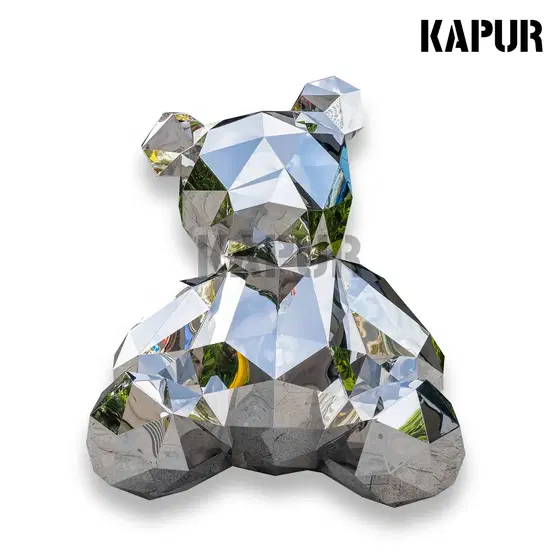 Polished stainless steel geometric bear animal sculpture standing on a paved outdoor plaza