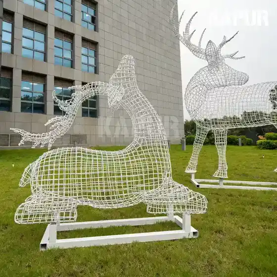 Polished stainless steel wire deer sculpture standing in a modern garden setting with reflective surface catching sunlight